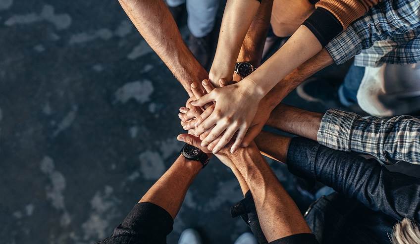 ourmission Top view of creative professionals putting their hands together as a symbol of teamwork, cooperation and unity. Stack of hands of men and woman.